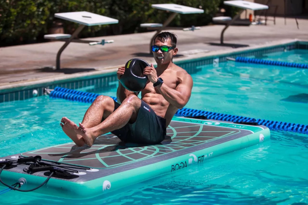 man holding a weight on a boga mat in the water