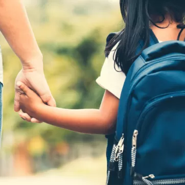 parent and child holding hands on their way to school