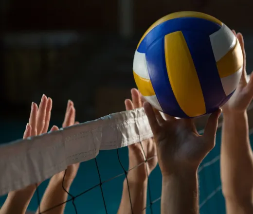 Volleyball at net with hands reaching